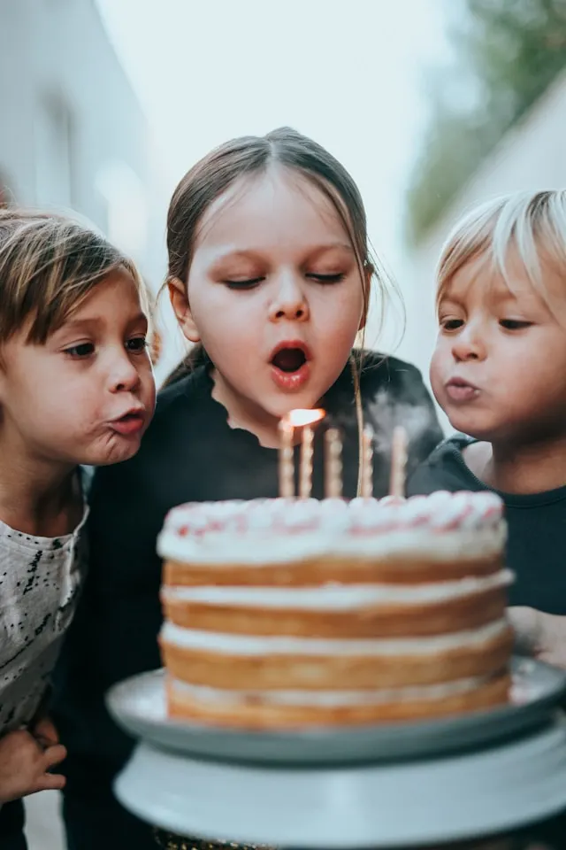 Children blowing out candles on birthday cake